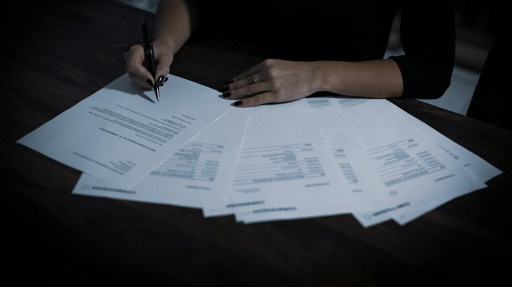A wooden table with papers and a pen