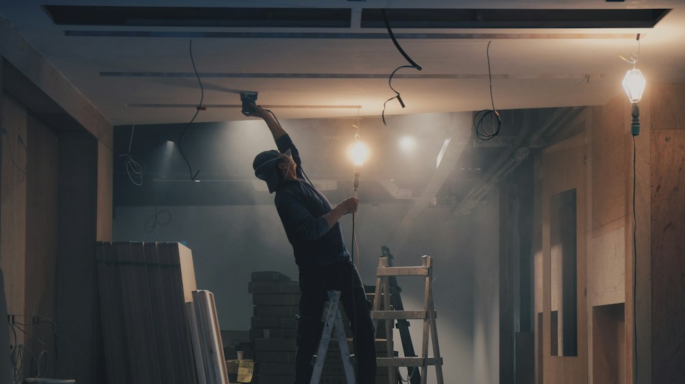 A person on a ladder working inside a room